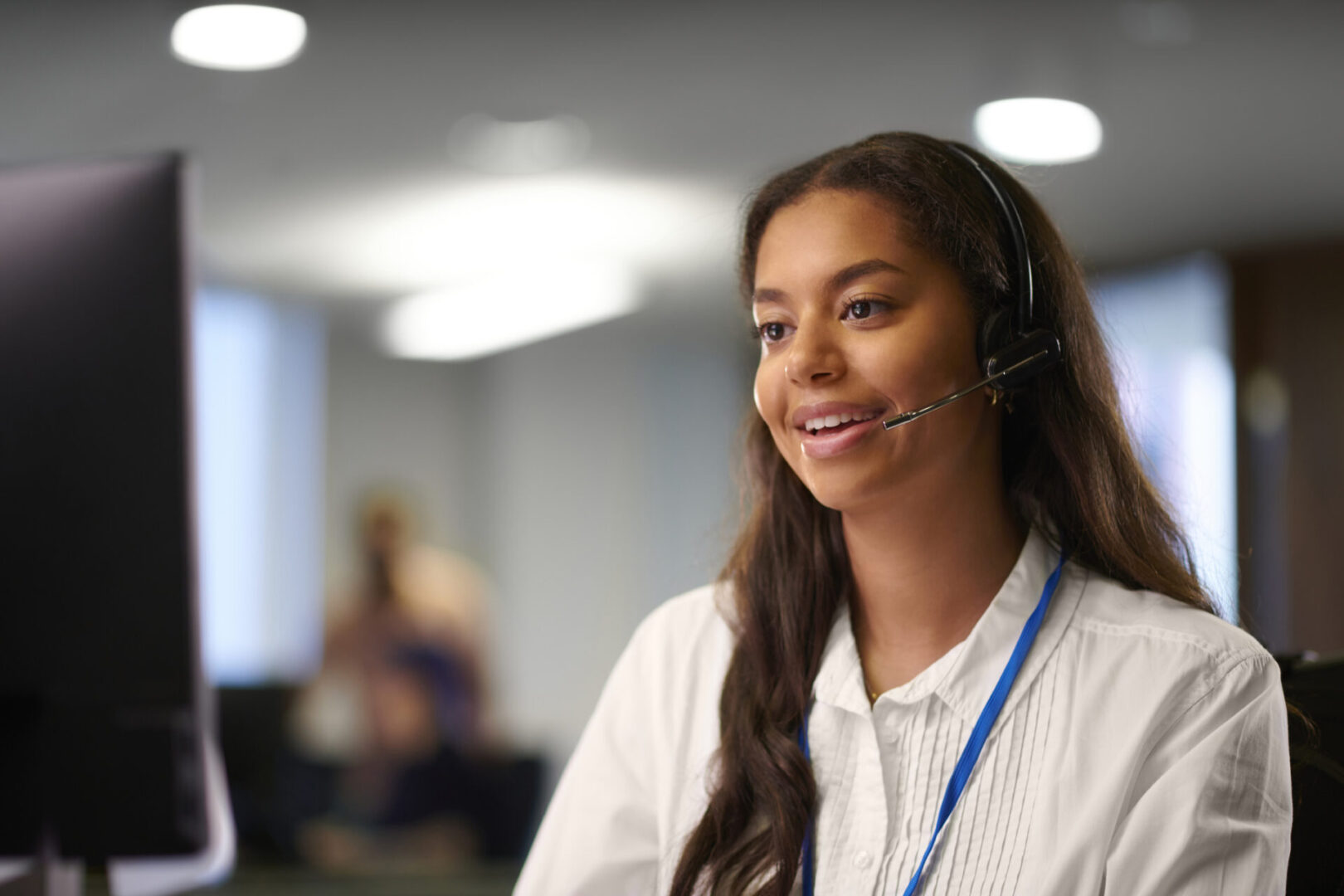 Smiling woman with headset at computer.